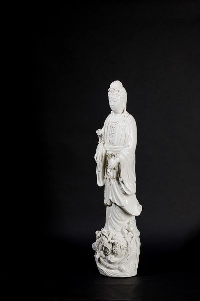 Figura in porcellana Blanc de Chine raffigurante Guanyin eretta su con vasetto, ramo fiorito e drago sulla base, Cina, inizi XX secolo  - Asta Arte Orientale - Associazione Nazionale - Case d'Asta italiane