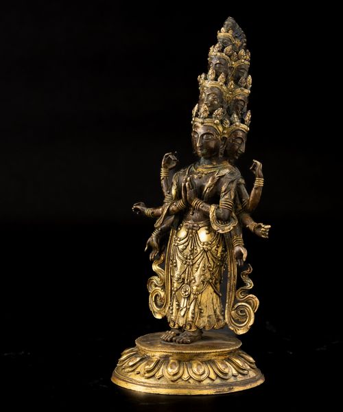 Figura di Ekadasamukha-Avalokitesvara stante su fiore di loto in bronzo parzialmente dorato con tracce di policromia, Cina, Dinastia Qing, XVIII secolo  - Asta Fine Chinese Works of Art - Associazione Nazionale - Case d'Asta italiane