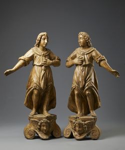 SCULTORE ITALIANO DEL XVII SECOLO - Coppia di angeli in legno scolpito poggianti su basi con volti di cherubini a rilievo tra volute