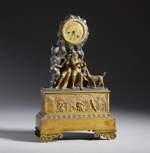 MANIFATTURA FRANCESE DEL XIX SECOLO - Orologio da tavolo in bronzo dorato con due figure e cane in un paesaggio roccioso, fronte della base decorata a rilievo