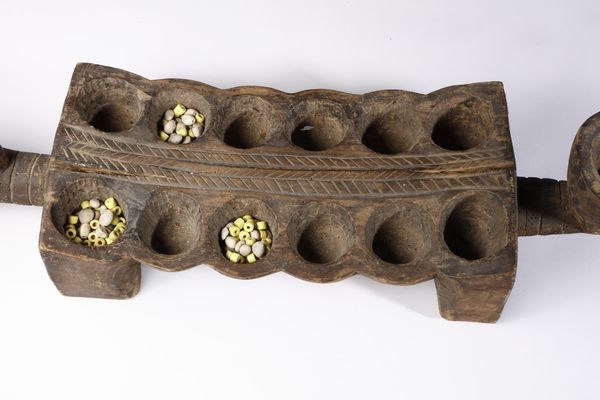 Dan - Costa d'Avorio/Liberia : Tavola da gioco Wari o Mancala a tredici buche e impugnatura a forma di testa antropomorfa.Legno a patina bruna.  - Asta Asta 422 | AFRICA, OCEANIA E AMERICHE - ARTIGIANATO AFRICANO: VARI COMMITTENTI E SELEZIONE DALLA COLLEZIONE BARTOLOMUCCI Online - Associazione Nazionale - Case d'Asta italiane