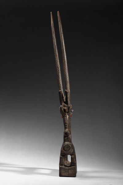 Bambara - Mali : Cimiero da danza  o Chiwara  a forma  di scultura zoomorfa  raffigurante un'antilope stilizzata con il suo piccolo in piedi sulla schiena.Legno duro a patina scura, metallo e tessuto.  - Asta Asta 422 | AFRICA, OCEANIA E AMERICHE - ARTIGIANATO AFRICANO: VARI COMMITTENTI E SELEZIONE DALLA COLLEZIONE BARTOLOMUCCI Online - Associazione Nazionale - Case d'Asta italiane