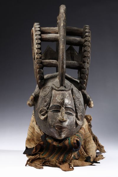 Igbo - Nigeria : Maschera antropomorfa con elaborata acconciatura. Legno a patina scura, pigmenti e tessuti.  - Asta Asta 422 | AFRICA, OCEANIA E AMERICHE - ARTIGIANATO AFRICANO: VARI COMMITTENTI E SELEZIONE DALLA COLLEZIONE BARTOLOMUCCI Online - Associazione Nazionale - Case d'Asta italiane