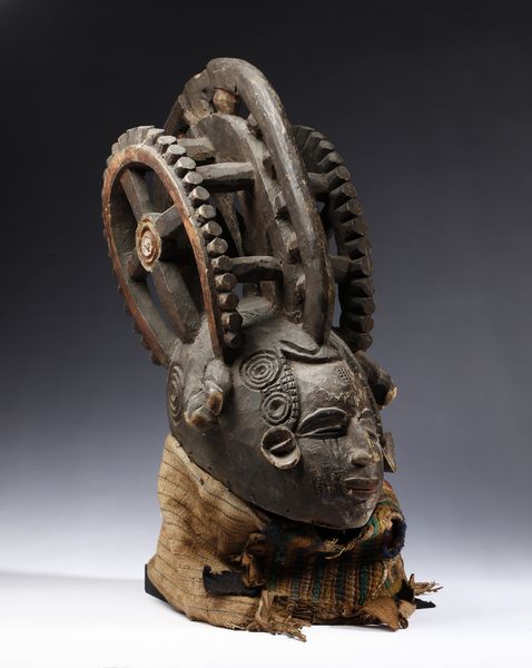 Igbo - Nigeria : Maschera antropomorfa con elaborata acconciatura. Legno a patina scura, pigmenti e tessuti.  - Asta Asta 422 | AFRICA, OCEANIA E AMERICHE - ARTIGIANATO AFRICANO: VARI COMMITTENTI E SELEZIONE DALLA COLLEZIONE BARTOLOMUCCI Online - Associazione Nazionale - Case d'Asta italiane