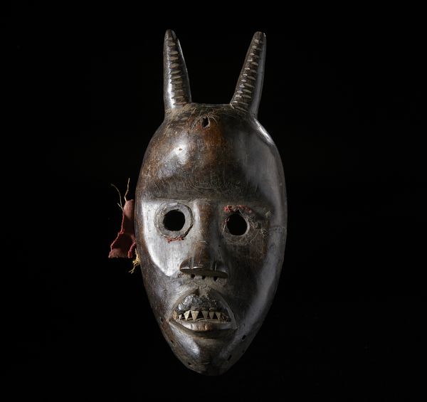 Dan - Costa d'Avorio/Liberia : Maschera Dan con corna. Legno duro a patina scura, fibre e metallo.  - Asta Asta 422 | AFRICA, OCEANIA E AMERICHE - ARTIGIANATO AFRICANO: VARI COMMITTENTI E SELEZIONE DALLA COLLEZIONE BARTOLOMUCCI Online - Associazione Nazionale - Case d'Asta italiane