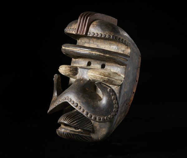 Bete - Costa d'Avorio : Maschera antropozoomorfa. Legno a patina scura, borchie metalliche, caolino e pigmenti.  - Asta Asta 422 | AFRICA, OCEANIA E AMERICHE - ARTIGIANATO AFRICANO: VARI COMMITTENTI E SELEZIONE DALLA COLLEZIONE BARTOLOMUCCI Online - Associazione Nazionale - Case d'Asta italiane