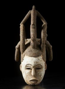 Igbo - Nigeria - Maschera a elmo antropomorfa femminile con elaborata acconciatura. Legno, colino e pigmento.