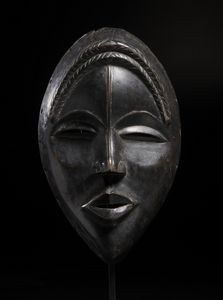 Dan - Costa d'Avorio/Liberia - Maschera antropomorfa con occhi a fessura e treccia frontale. Legno duro a patina nera.