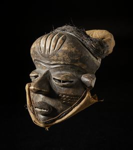 Pende - Repubblica Democratica del Congo : Maschera antropomorfa. Legno duro a patina scura e tessuti in rafia.  - Asta Asta 422 | AFRICA, OCEANIA E AMERICHE - ARTIGIANATO AFRICANO: VARI COMMITTENTI E SELEZIONE DALLA COLLEZIONE BARTOLOMUCCI Online - Associazione Nazionale - Case d'Asta italiane