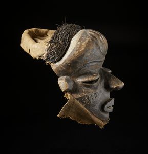 Pende - Repubblica Democratica del Congo : Maschera antropomorfa. Legno duro a patina scura e tessuti in rafia.  - Asta Asta 422 | AFRICA, OCEANIA E AMERICHE - ARTIGIANATO AFRICANO: VARI COMMITTENTI E SELEZIONE DALLA COLLEZIONE BARTOLOMUCCI Online - Associazione Nazionale - Case d'Asta italiane