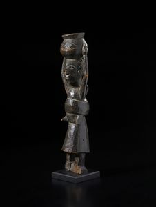 Baule - Costa d'Avorio : Scultura antropomorfa femminile con bambino sul dorso e con vaso sul capo. Legno duro a patina scura.  - Asta Asta 422 | AFRICA, OCEANIA E AMERICHE - ARTIGIANATO AFRICANO: VARI COMMITTENTI E SELEZIONE DALLA COLLEZIONE BARTOLOMUCCI Online - Associazione Nazionale - Case d'Asta italiane