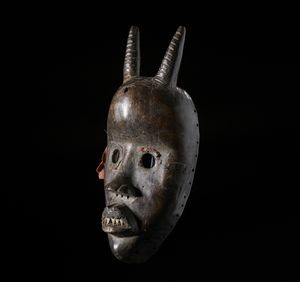 Dan - Costa d'Avorio/Liberia : Maschera Dan con corna. Legno duro a patina scura, fibre e metallo.  - Asta Asta 422 | AFRICA, OCEANIA E AMERICHE - ARTIGIANATO AFRICANO: VARI COMMITTENTI E SELEZIONE DALLA COLLEZIONE BARTOLOMUCCI Online - Associazione Nazionale - Case d'Asta italiane