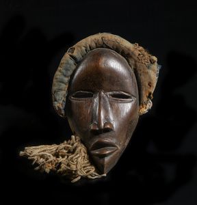 Dan - Costa d'Avorio/Liberia - Maschera antropomorfa. Legno a patina marrone, corda e fibre.