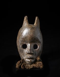 Dan - Costa d'Avorio/Liberia - Maschera antropozoomorfa con occhi circolari e corna. Legno duro a patina scura e tessuto.