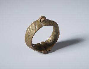 Artigianato africano : Bracciale con snodo e chiusura decorato con incisioni geometriche. Lega di rame.  - Asta Asta 422 | AFRICA, OCEANIA E AMERICHE - ARTIGIANATO AFRICANO: VARI COMMITTENTI E SELEZIONE DALLA COLLEZIONE BARTOLOMUCCI Online - Associazione Nazionale - Case d'Asta italiane