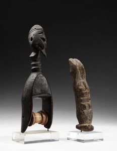 Dogon - Mali - Lotto composto da una puleggia da telaio con testa antropomorfa e da una piccola scultura antropomorfa stilizzata o Nommo, antenato primordiale, in piedi con le braccia alzate. Legno.