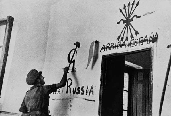 Robert Capa, : A member of the Internatinal Brigade applies some of his propaganda in a village wall  - Asta Fotografia - Associazione Nazionale - Case d'Asta italiane