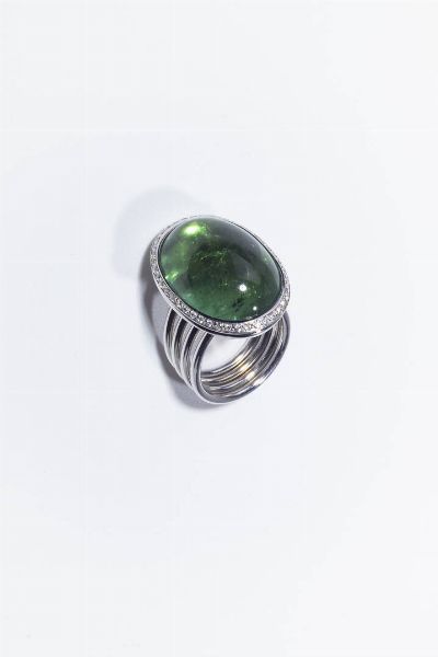 ANELLO : Peso gr 27 Misura 13 (53) in oro bianco  sommit con grande tormalina verde ovale cabochon di ct. 27 ca  contornata da diamanti taglio brillante per totali ct. 0 48 ca. Particolare gambo composto da quattro anelli mobili.  - Asta Gioielli - Associazione Nazionale - Case d'Asta italiane