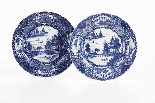 Coppia di piatti in porcellana blu e bianca con raffigurazioni di paesaggi con pagode entro riserve, Cina, Dinastia Qing, epoca Qianlong (1736-1796)  - Asta Arte orientale  - Associazione Nazionale - Case d'Asta italiane