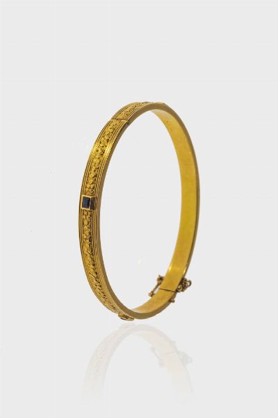 BRACCIALE : Peso gr 15 6 rigido  in oro giallo 14 Kt  anni '30  parte centrale lavorata a motivo floreale e quattro zaffiri sintetici a decoro.  - Asta Gioielli - Associazione Nazionale - Case d'Asta italiane