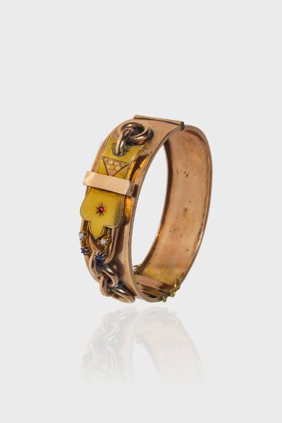 BRACCIALE : Peso gr 18 1 rigido  in oro rosa 9 Kt  XIX secolo  parte superiore lavorata con motivo a fibbia ed impreziosita da piccole perline e due gemme sintetiche blu. Ammaccature.  - Asta Gioielli - Associazione Nazionale - Case d'Asta italiane