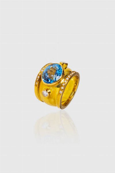 ANELLO : Peso gr 12 Misura 8 (48) in oro giallo  a fascia  con al centro topazio azzurro taglio ovale e diamanti taglio brillante a decoro per totali ct 0 30 ca  - Asta Gioielli  - Associazione Nazionale - Case d'Asta italiane