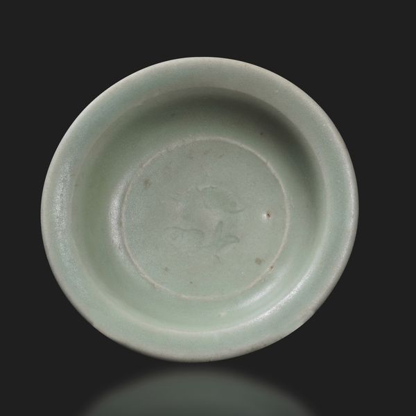 Piattino in porcellana celadon a decoro di coppia di pesci incussi nel cavetto, Cina, Dinastia Song, XIII secolo  - Asta Fine Asian Works of Art - Associazione Nazionale - Case d'Asta italiane