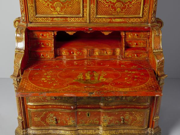 MANIFATTURA VENEZIANA DEL XVIII SECOLO : Eccezionale cassettone a ribalta con alzata, in legno laccato a fondo rosso e parzialmente dorato, fittamente decorato a motivi di ghirlande fiorite che racchiudono scene a 'chinoiseries' con magots, architetture e paesaggi orientali. alzata con cimasa di linea spezzata e due ante celanti sei vani con ornato floreale e una nicchia centrale, corpo inferiore di forma mossa con due cassetti sul fronte sormontati da anta calatoia con interni suddivisi in cassettini e vano centrale. fianchi concavi e lesene evidenziate da volute, piedi a mensola laccati a fondo verde scuro  - Asta Asta 460 | ARTE ANTICA E DEL XIX SECOLO - Da una dimora veneta e altre committenze Tradizionale - Associazione Nazionale - Case d'Asta italiane