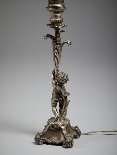 ARGENTIERE ITALIANO DEL XX SECOLO : Lampada in argento con fusto in foggia di putto che sorregge uno stelo vegetale, base poggiante su piedi a ricciolo  - Asta Asta 472 | ARTE ANTICA E DEL XIX SECOLO Virtuale - Associazione Nazionale - Case d'Asta italiane