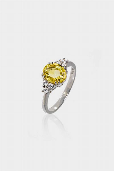 ANELLO : Peso gr 3 7 Misura 15 (55) in oro bianco  al centro zaffiro giallo taglio ovale di ct 1 80 ca ed ai lati sei diamanti taglio brillante per totali ct 0 15 ca  probabile colore G-H  purezza IF-VVS  - Asta Gioielli  - Associazione Nazionale - Case d'Asta italiane