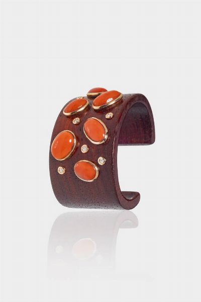 BRACCIALE : rigido in legno curvato  sommit con ovali in corallo rosso mediterraneo cabochon e oro rosa 9 Kt. Diamanti taglio brillante per totali ct 0 21 ca Corredato di certificato del perito Caviglia di Roma  - Asta Gioielli  - Associazione Nazionale - Case d'Asta italiane