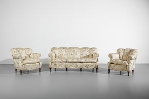 MANIFATTURA DEL XIX-XX SECOLO - Divano a tre posti e due poltrone imbottite, interamente rivestiti in tessuto a motivi floreali su fondo chiaro, gambe arcuate in legno intagliato